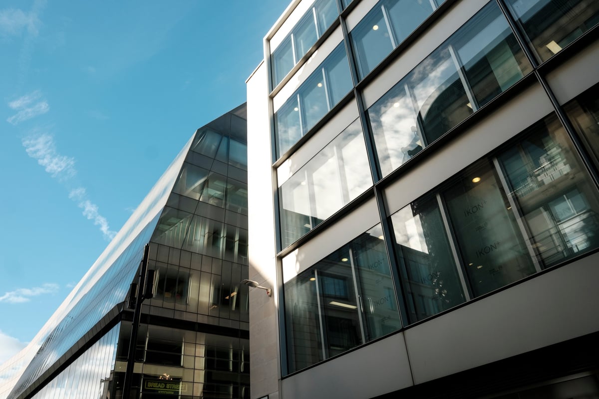 Contemporary commercial buildings featuring geometric glass facades and reflections of the blue sky, representing modern architecture, business, and urban development