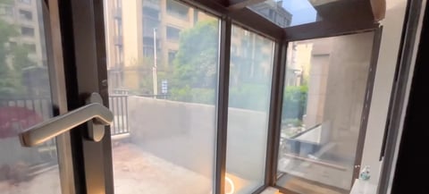 Modern glass balcony doors with dark metal frame opening to urban city view with buildings