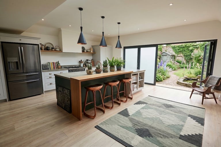Modern open-concept kitchen and dining area with wood island, pendant lights, stainless steel appliances, and garden view through large sliding doors