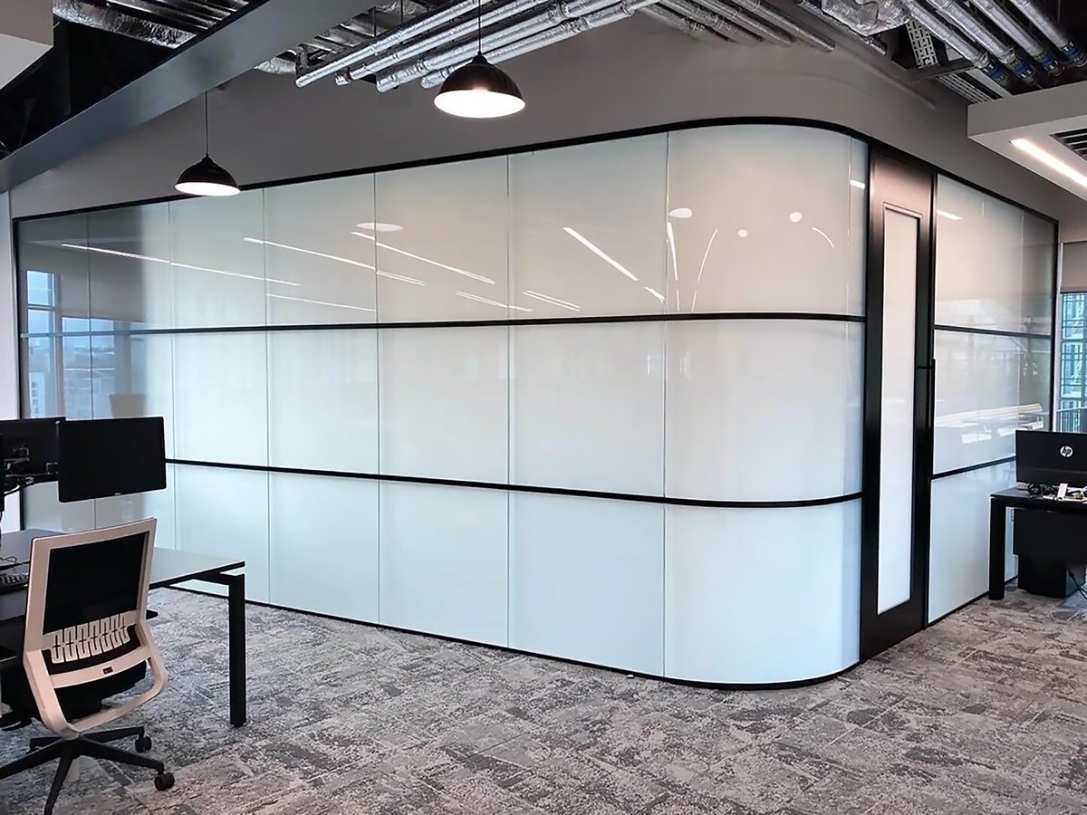 Modern frosted glass office partition wall in contemporary workspace with suspended ceiling lights and carpeted floor