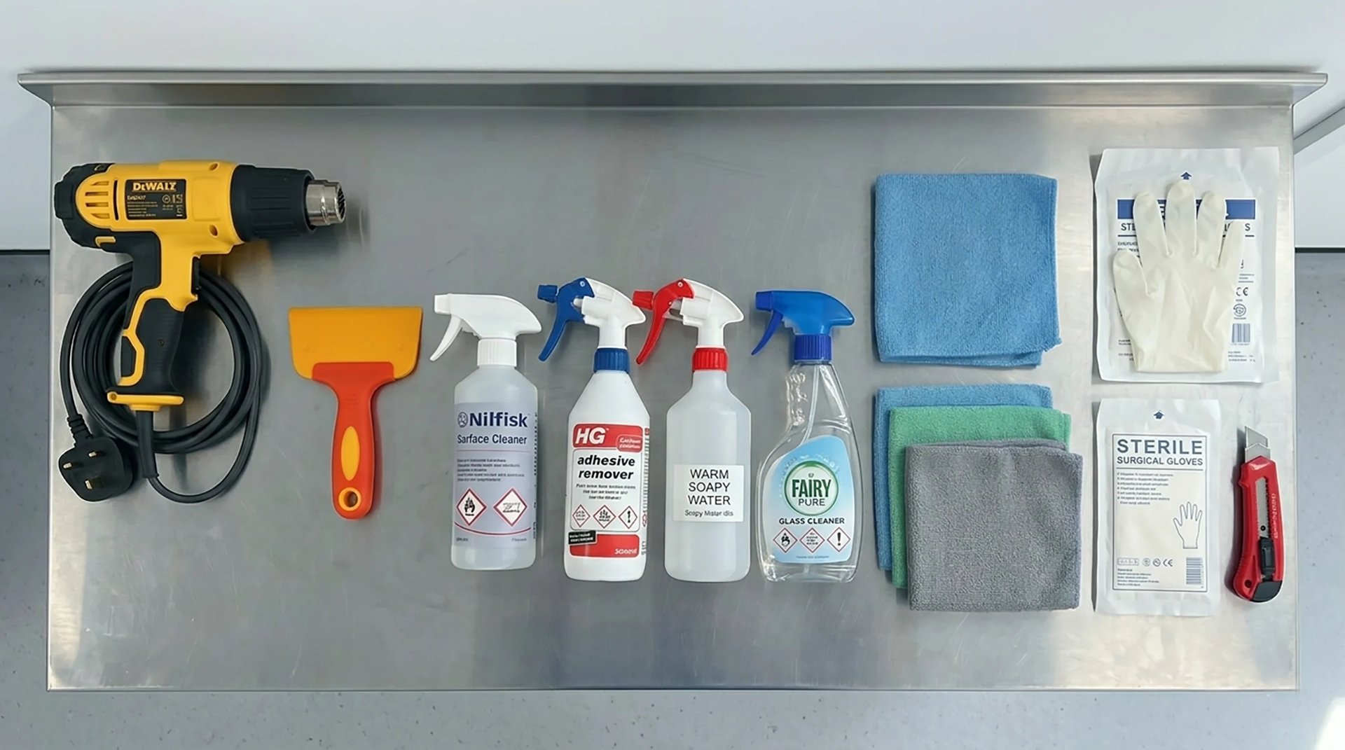 Organized tool collection displayed on metal pegboard including drill, hammer, cleaning supplies, microfiber cloths, and gloves