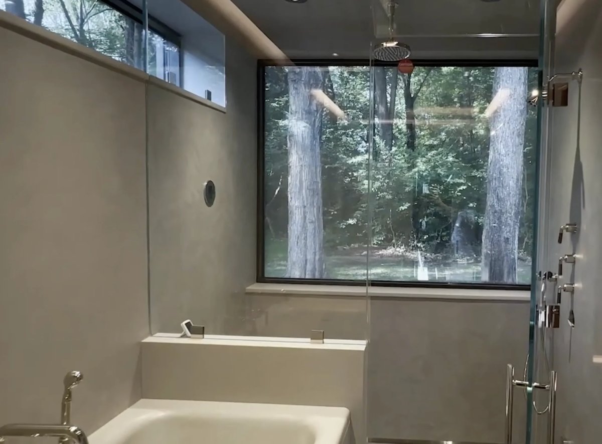 Modern bathroom with soaking tub and large window overlooking forest trees