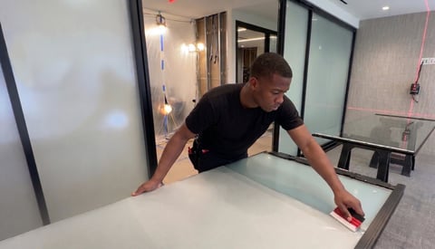 Man in black shirt doing a plank exercise on a white kitchen counter in a modern bathroom